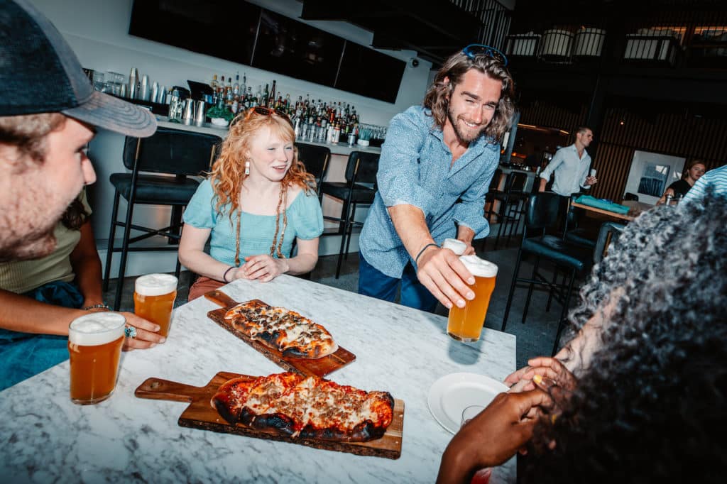 People enjoying pizza and beer at the bar