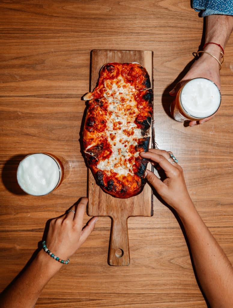 2 people enjoying pizza and beer