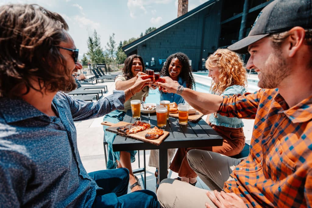 friends cheer cocktails around outdoor table