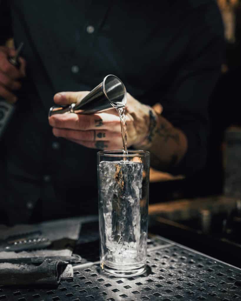 Close up of bartender pouring shot into cocktail