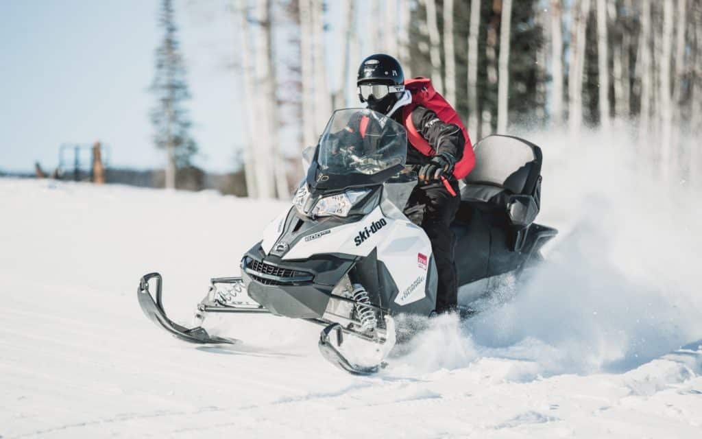 snowmobile riding through the snow with aspen trees in the background