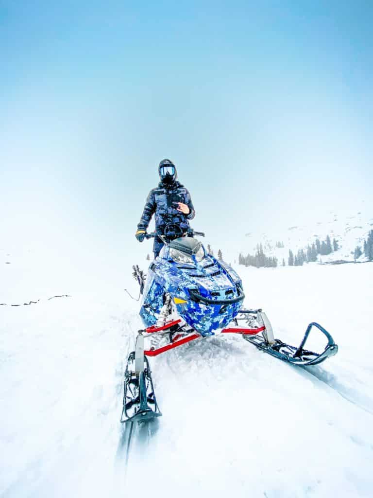 Straight on person standing on snow mobile